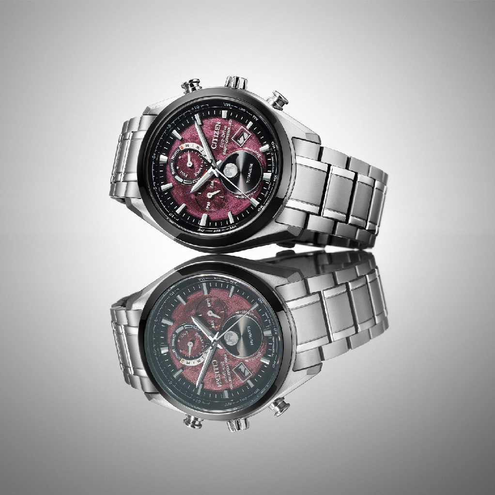 Citizen watch with a red face and titanium band, reflected on a surface.