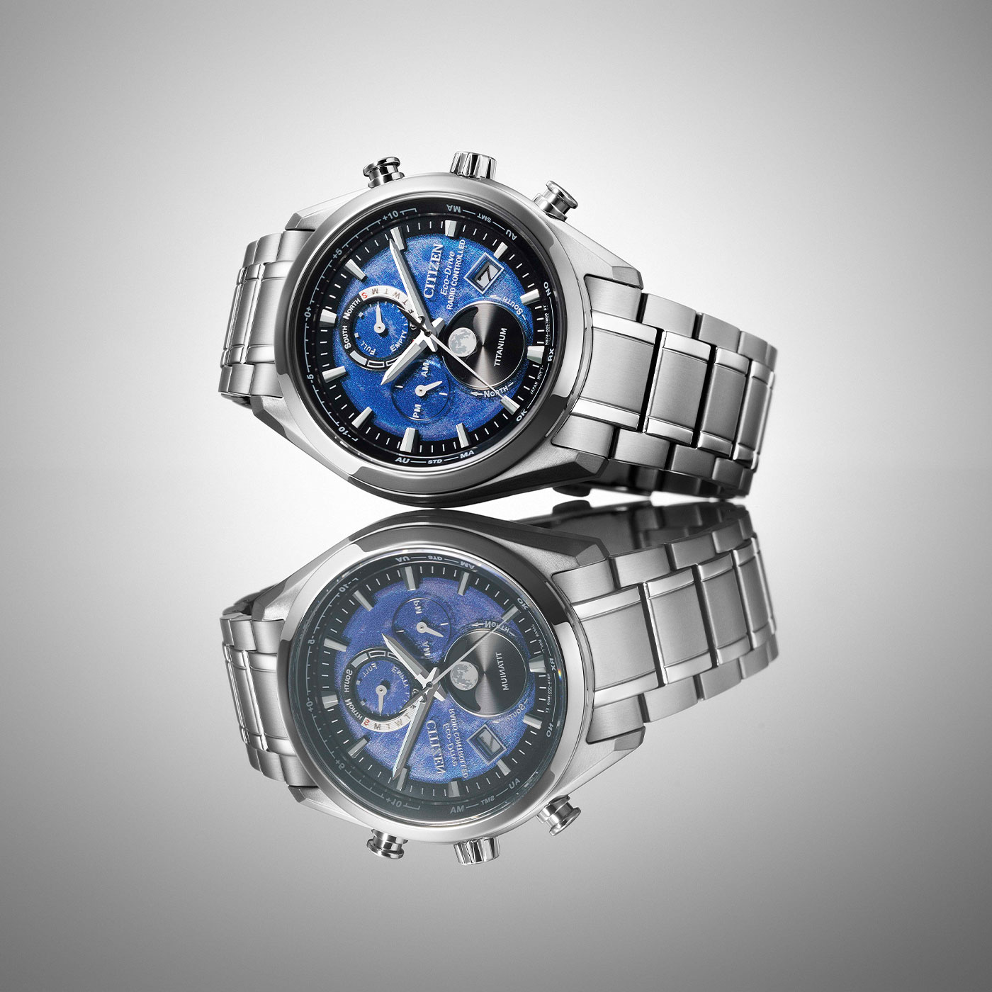 Citizen watch with blue face and titanium band, reflected on a surface.