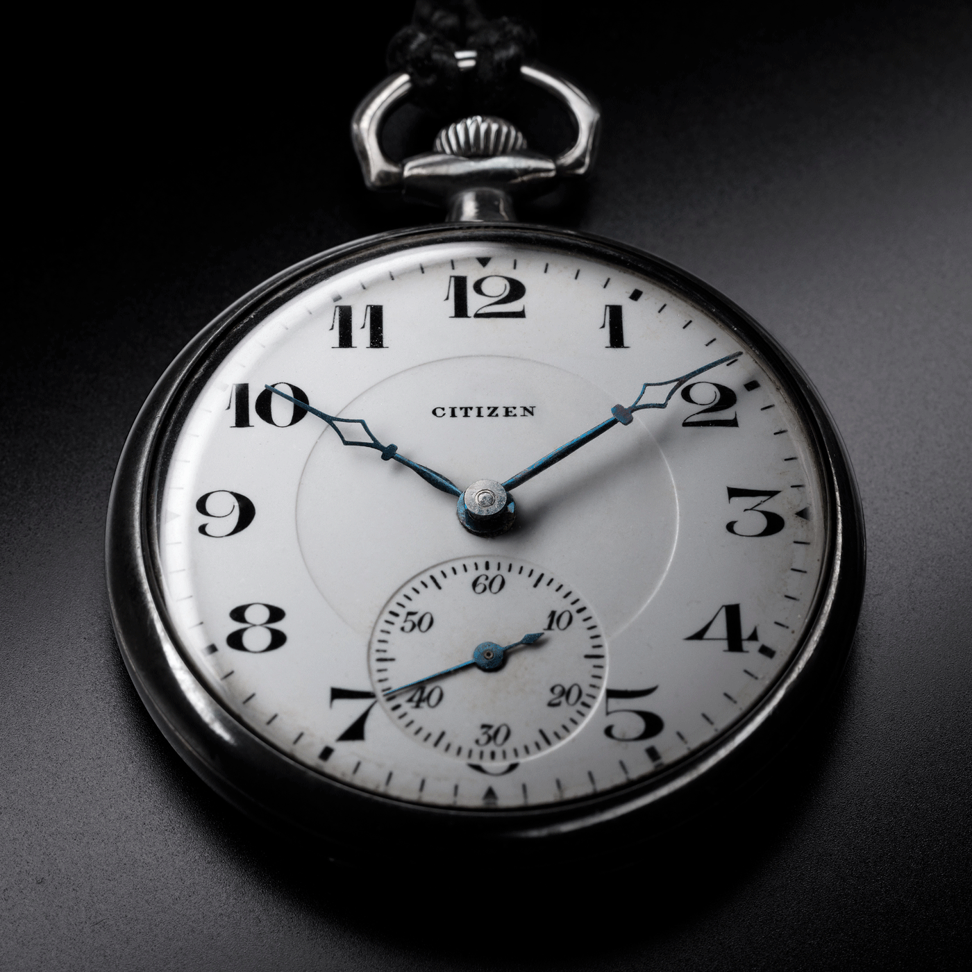 Close-up of a Citizen pocket watch, showing the time and details on a black background.