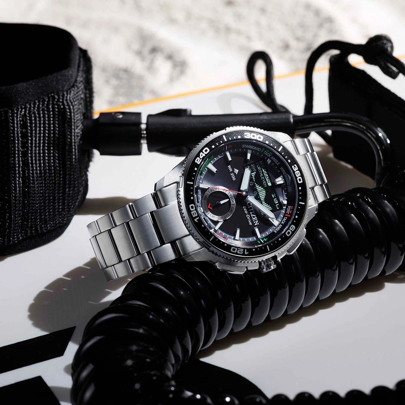 A watch on a surfboard with a leash and coiled cord.