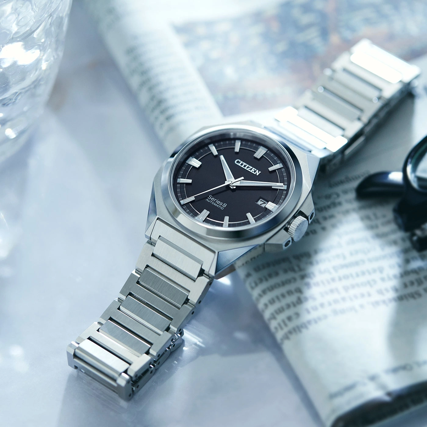 Citizen Series 8 watch on newspaper, black dial, silver bracelet, elegant design