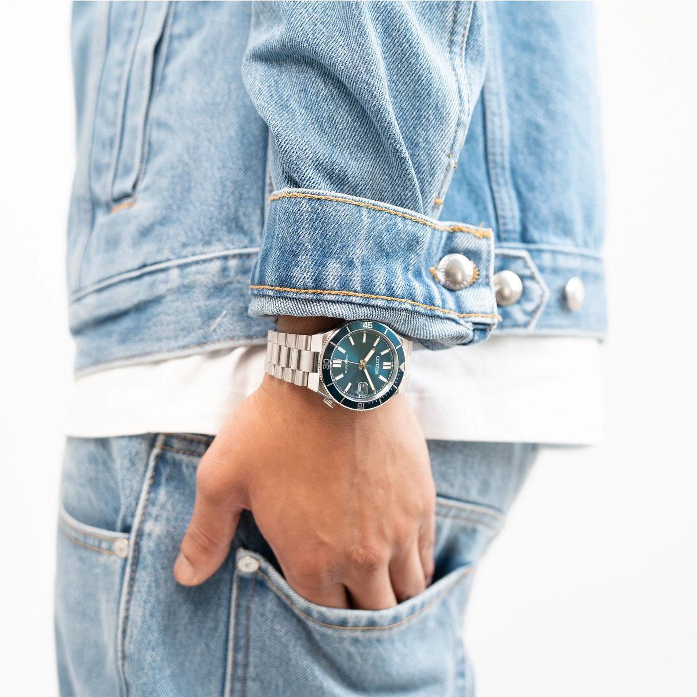 Man wearing a denim jacket and jeans with a watch.