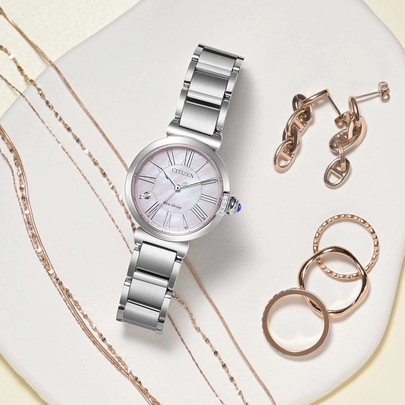 A collection of elegant jewelry including a Citizen watch, earrings, and rings.