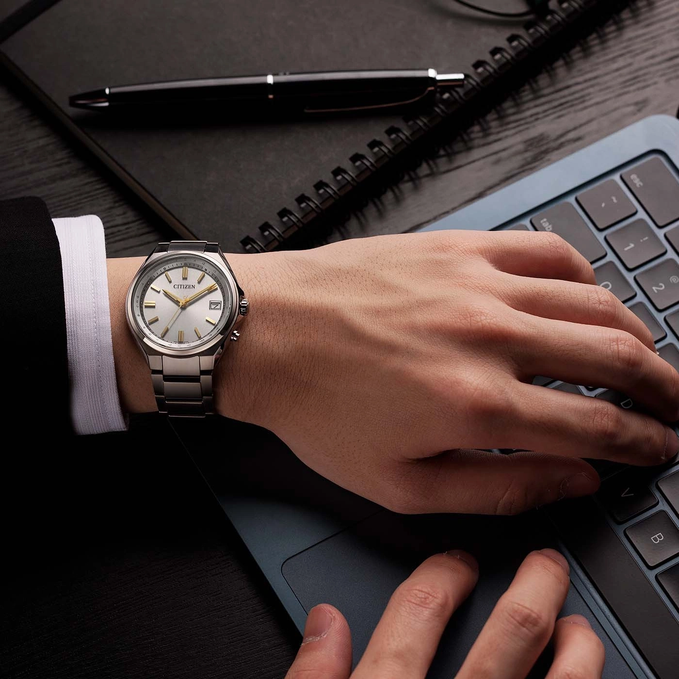 Man wearing a watch typing on a laptop.
