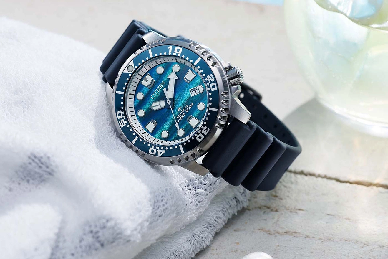 A blue Citizen Eco-Drive diver's watch with a rubber strap rests on a white towel.