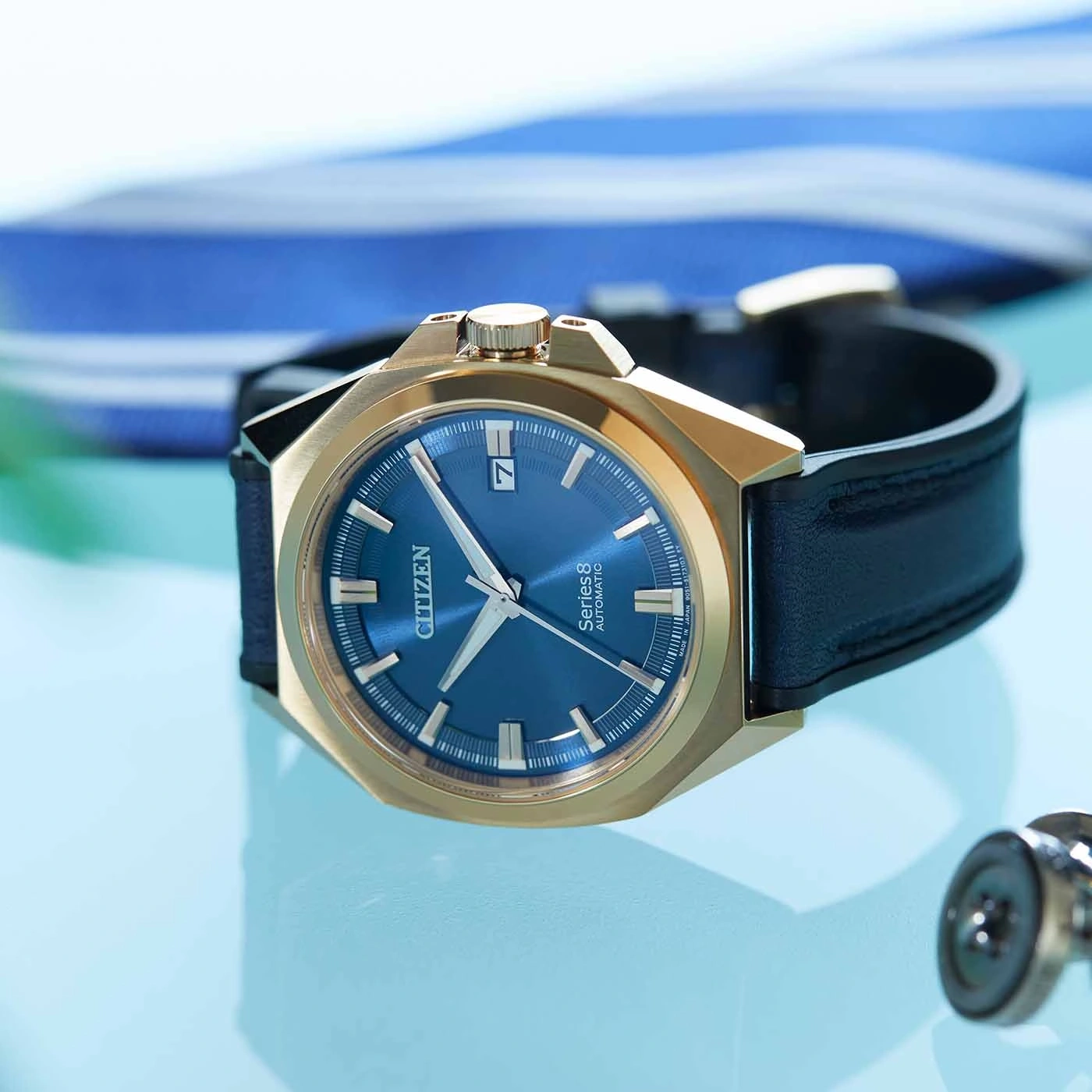 Citizen watch with blue face and gold case on a blue surface.