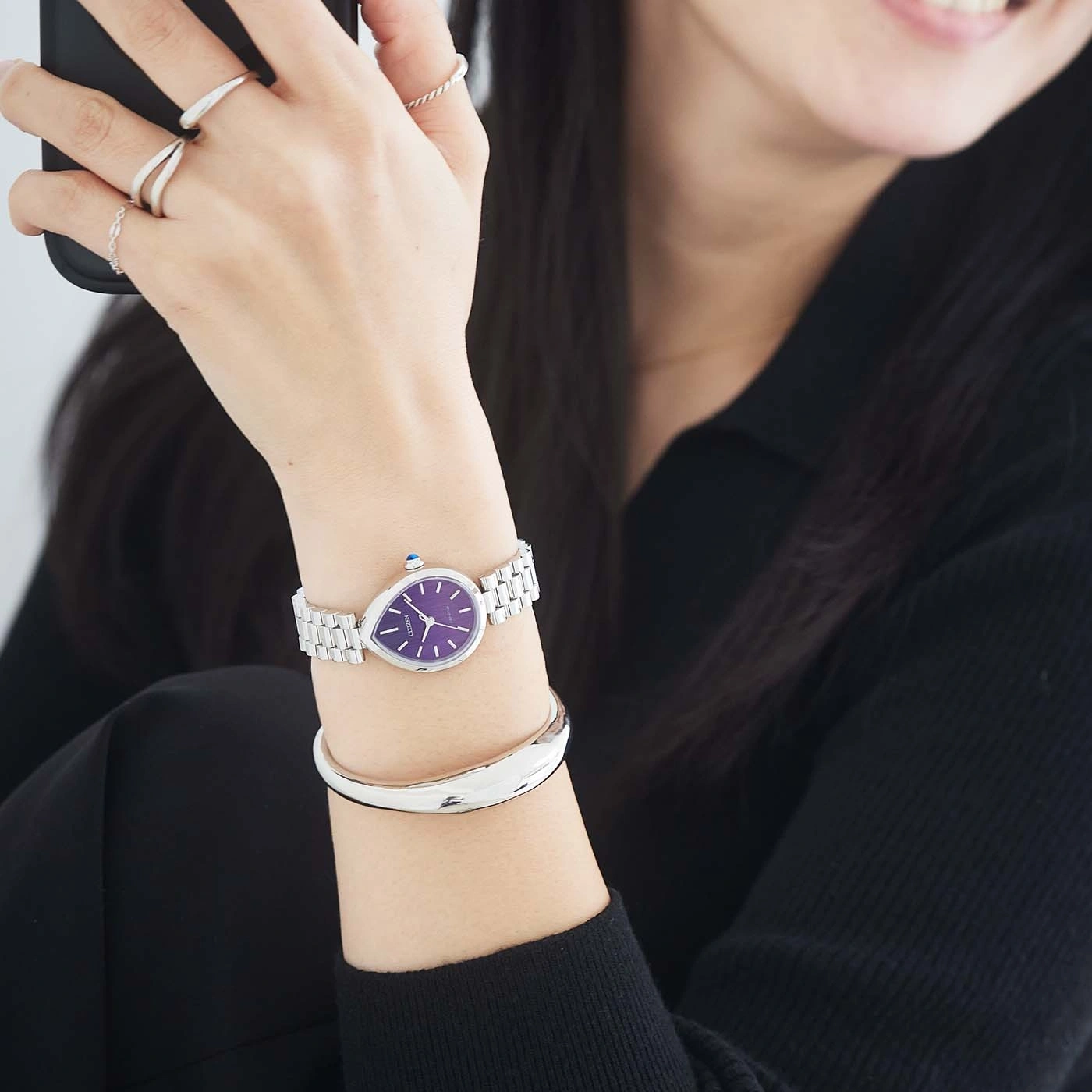 Woman wearing a purple-faced watch and silver bracelet