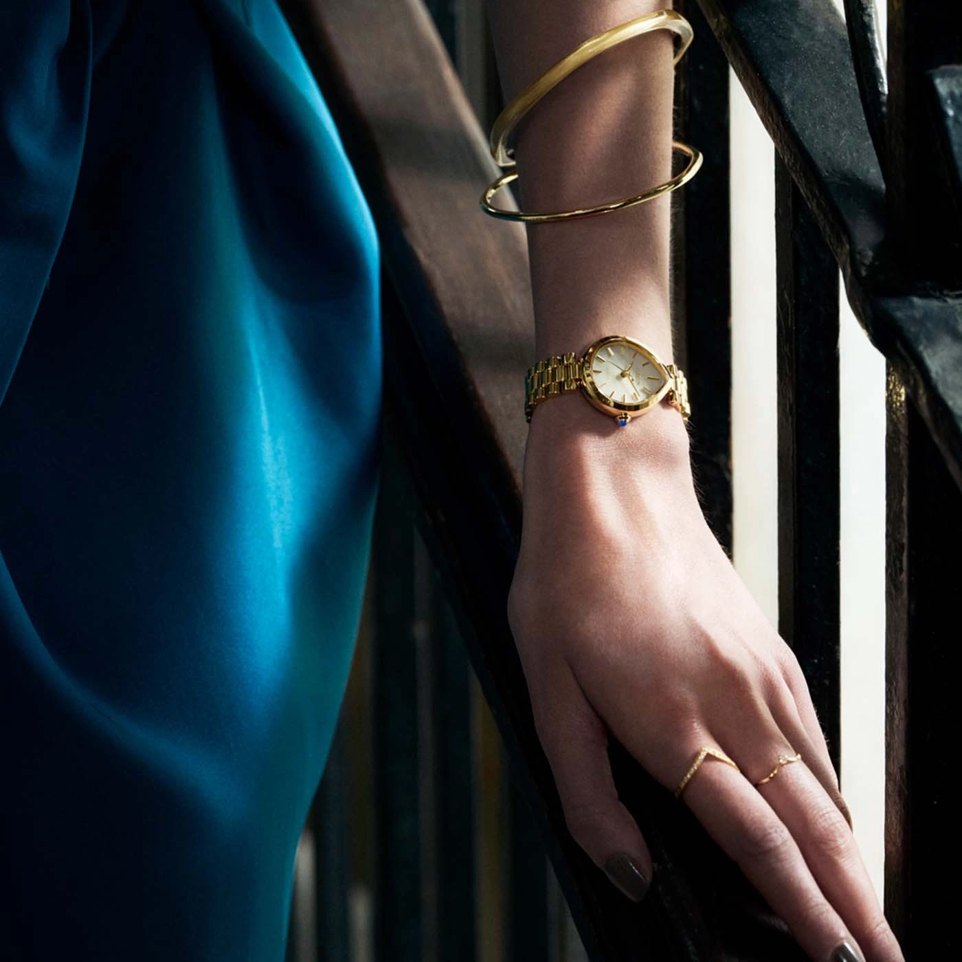 Woman's hand with watch, bracelets, and rings on stairs.