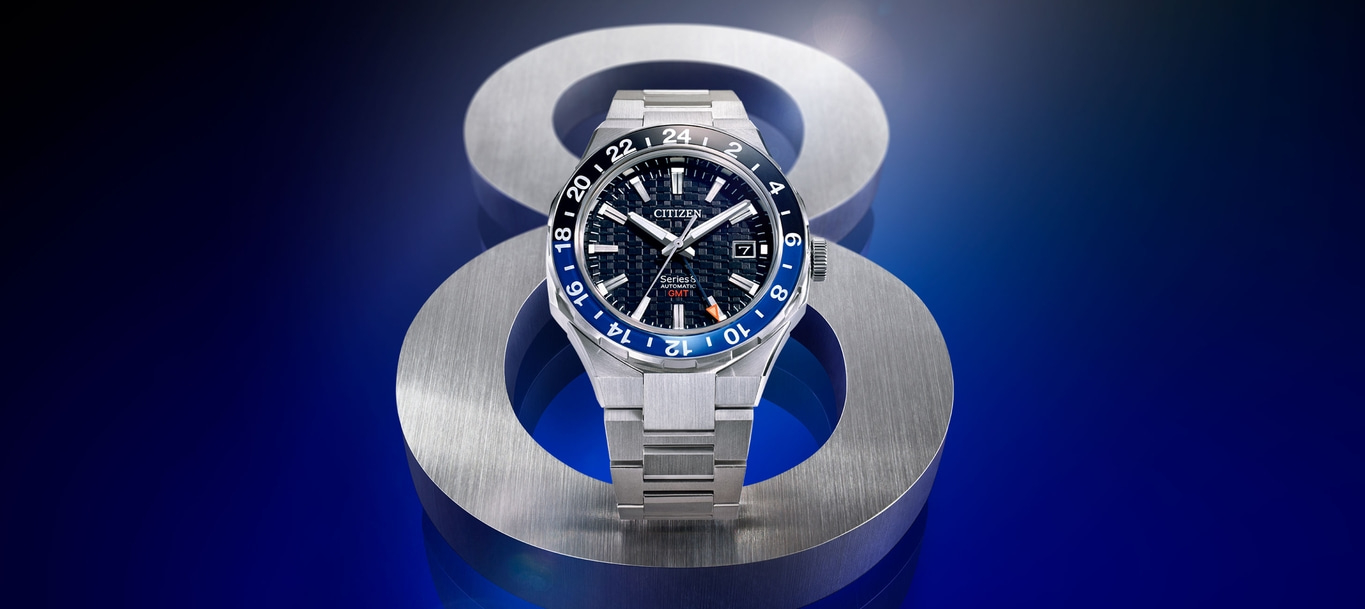 Citizen Series 8 automatic GMT watch on a metallic stand, blue background.