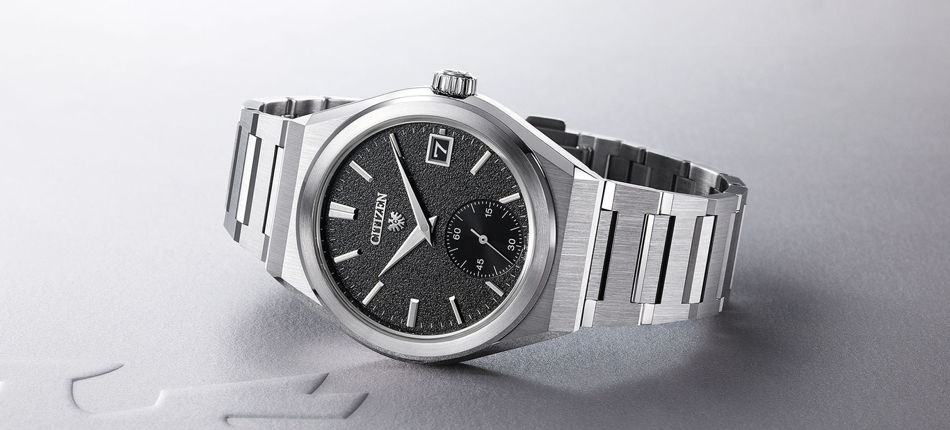 Citizen-Uhr mit schwarzem Zifferblatt und silbernem Armband auf grauem Untergrund