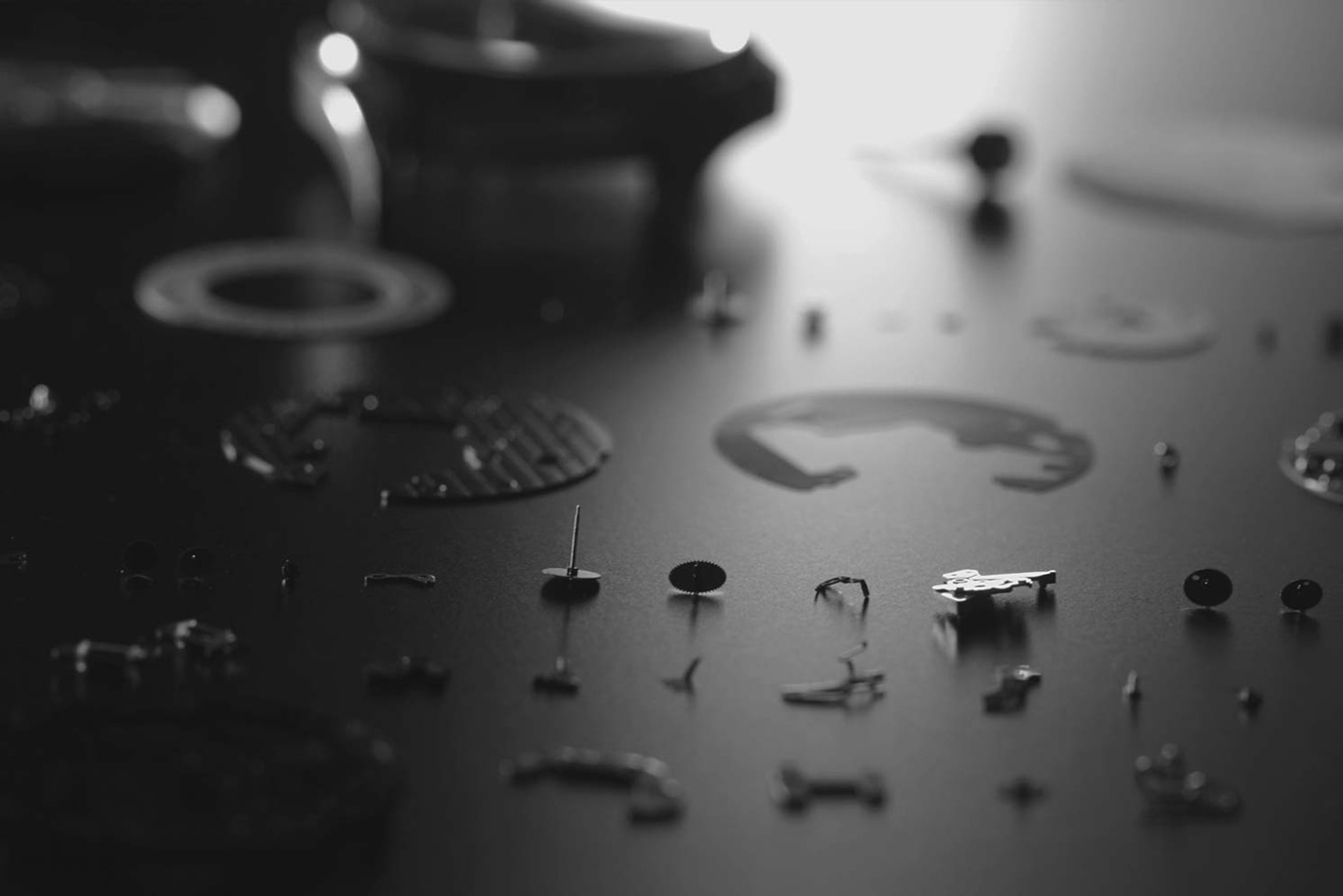 Uhrenteile auf dunkler Oberfläche verstreut, Nahaufnahme, monochrom, detailliert.
