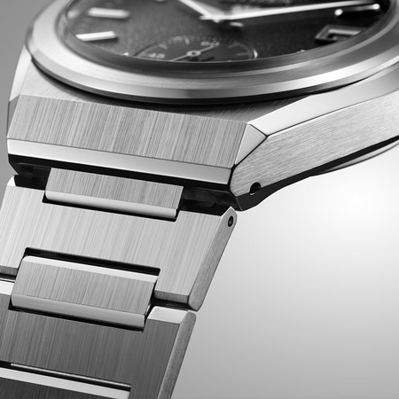 Nahaufnahme einer silbernen Uhr mit gebürsteter Metalloberfläche und dunklem Zifferblatt.