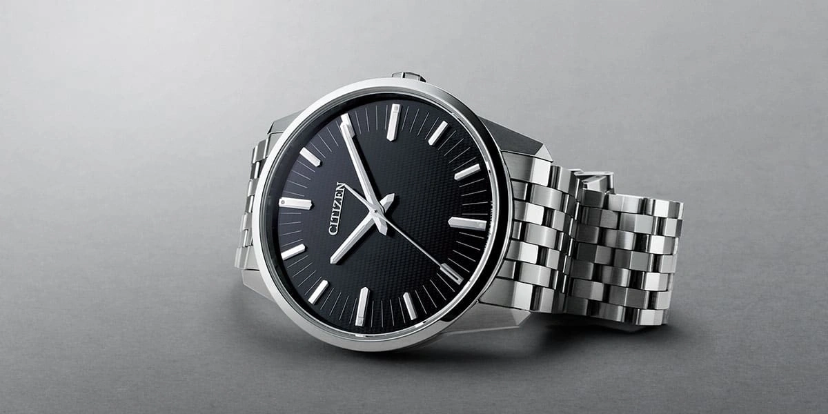 Citizen watch with a black face and silver band on a gray surface