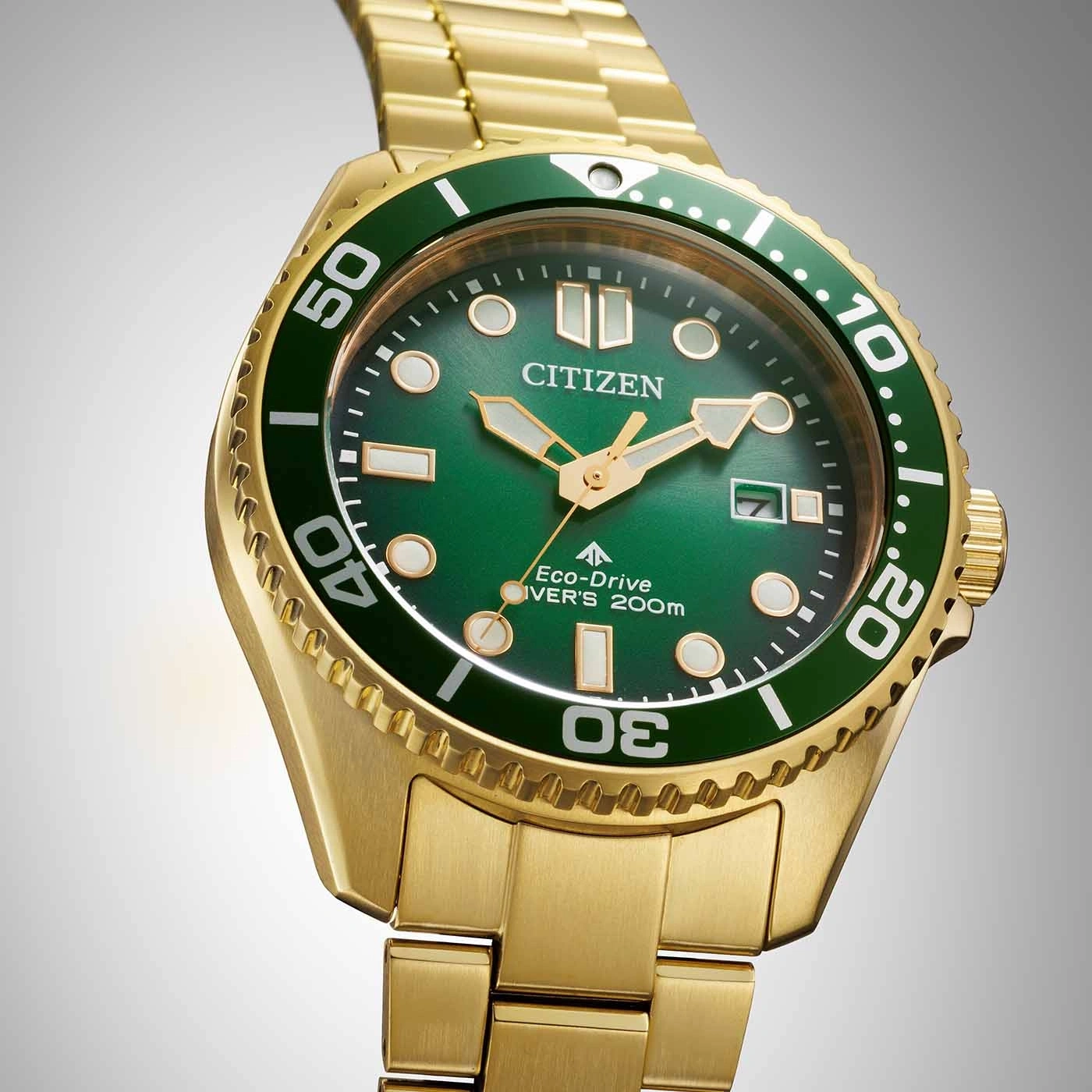 Gold Citizen watch with green face and bezel, close-up shot.