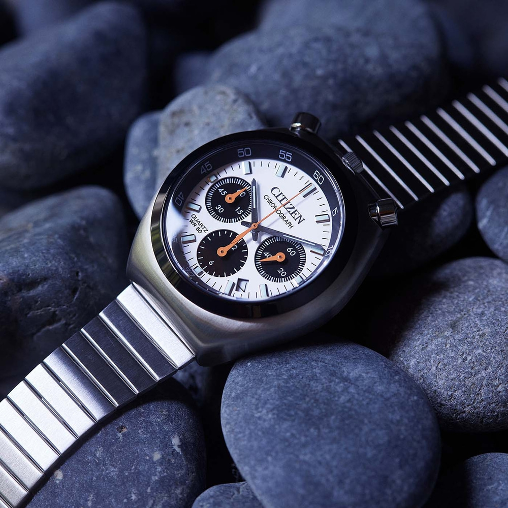 A close-up shot of a Citizen chronograph watch on dark stones.