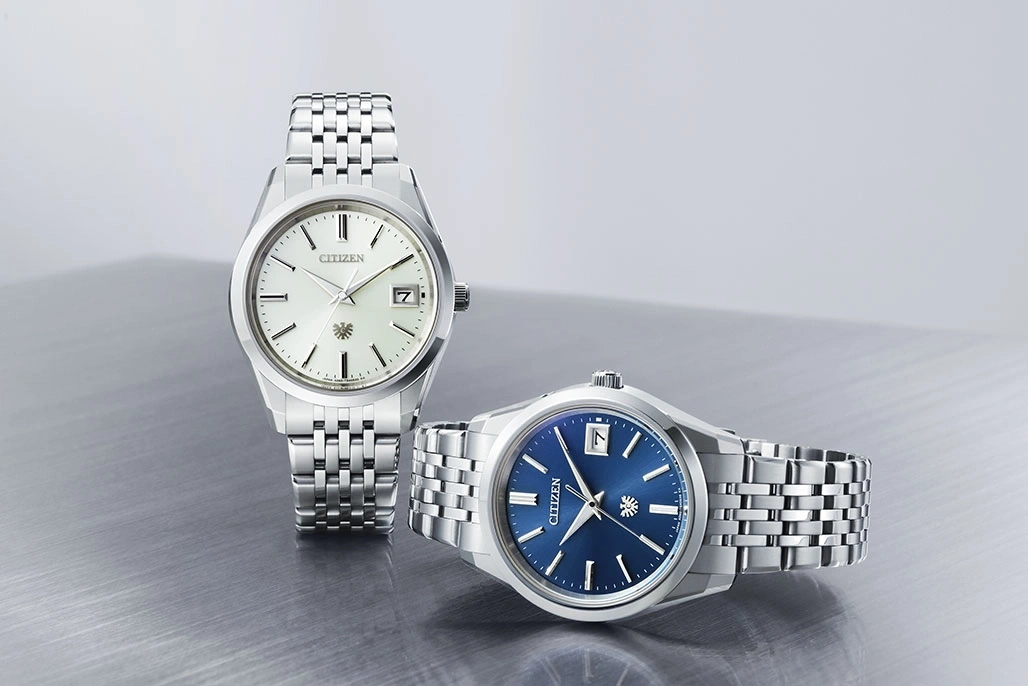 Two Citizen watches with silver straps and different colored faces.