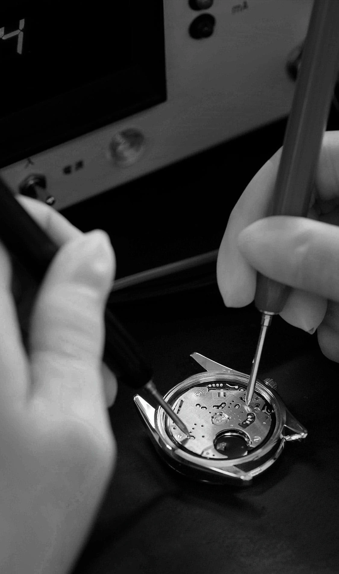 Watch repair with tools, close-up of hands and watch mechanism.