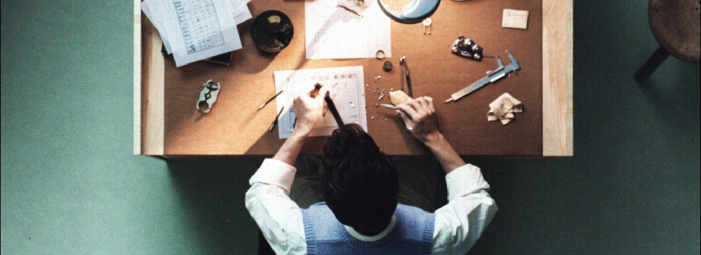 A person working on a table with tools and papers, overhead shot.