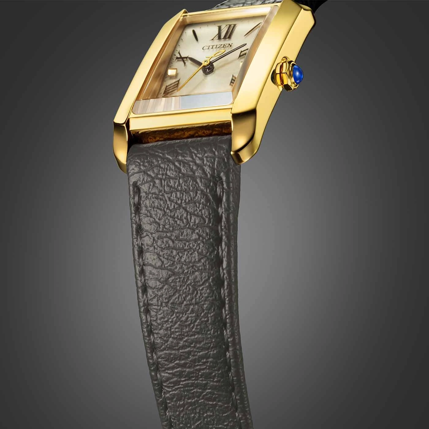 Gold watch with a rectangular face and a leather strap.