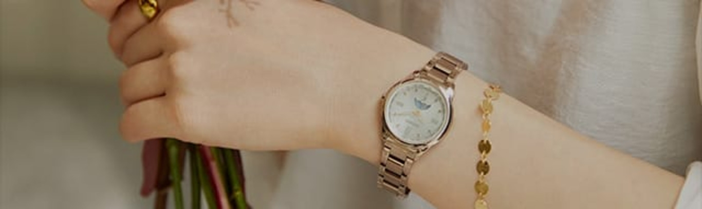 A person wearing a watch and a bracelet, holding flowers.