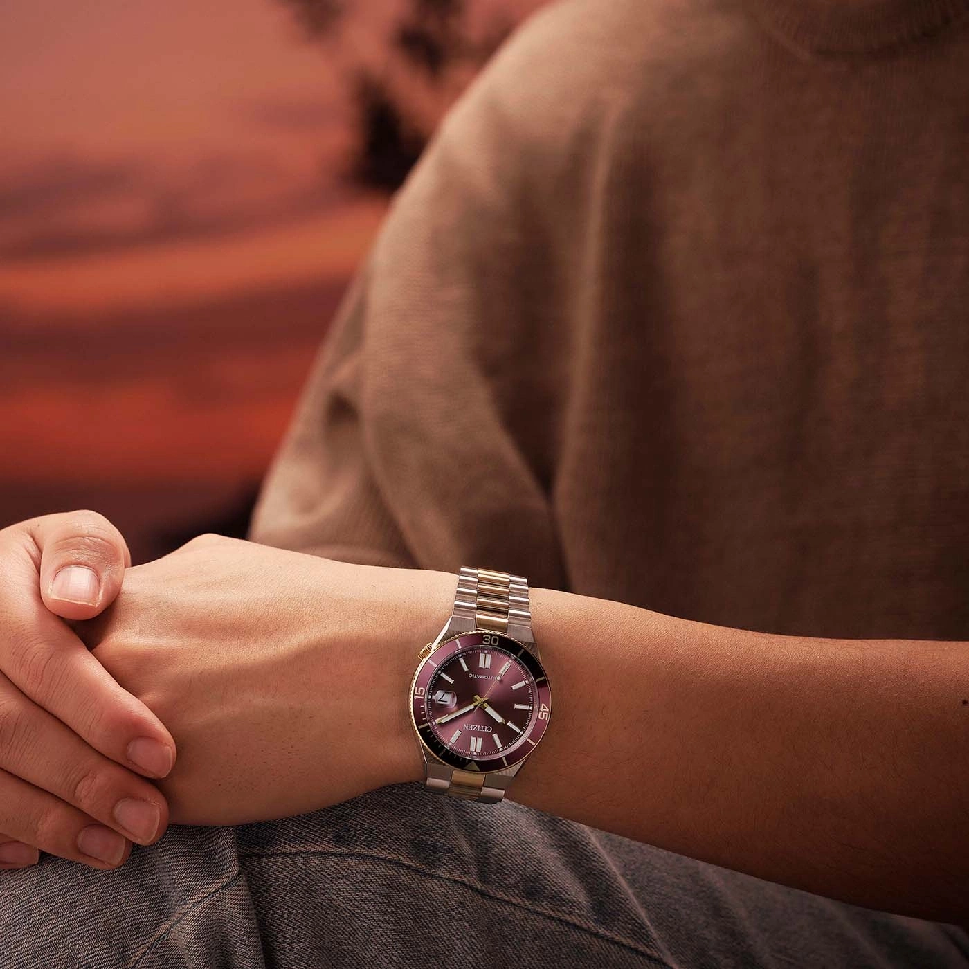 Man wearing a watch with a purple dial and metal band.