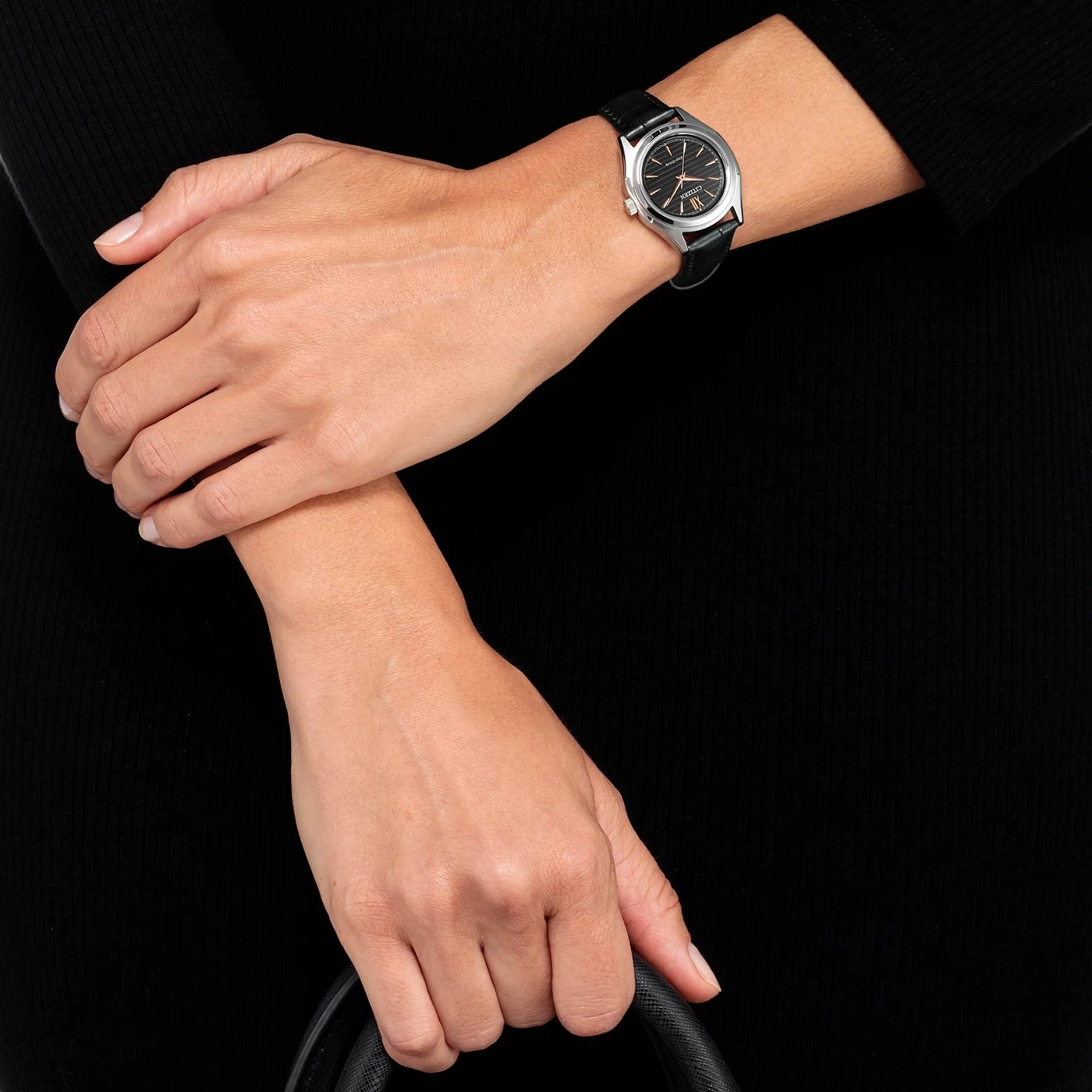 Woman wearing a watch, holding a bag, black dress, close-up shot