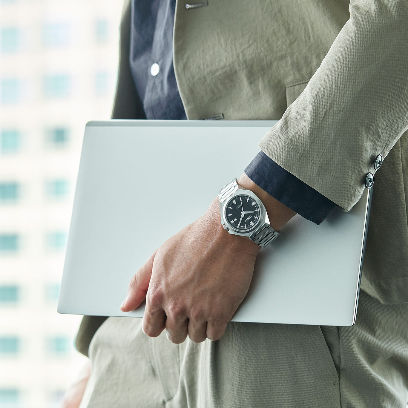 Man holding laptop, wearing watch and suit. Business professional.