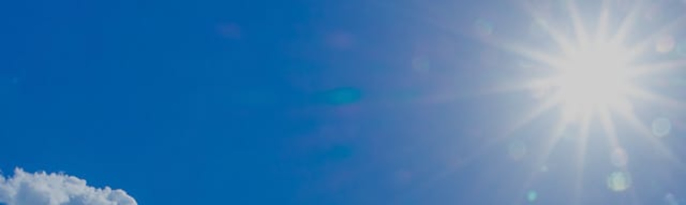 Bright sun in a clear blue sky with a few clouds.
