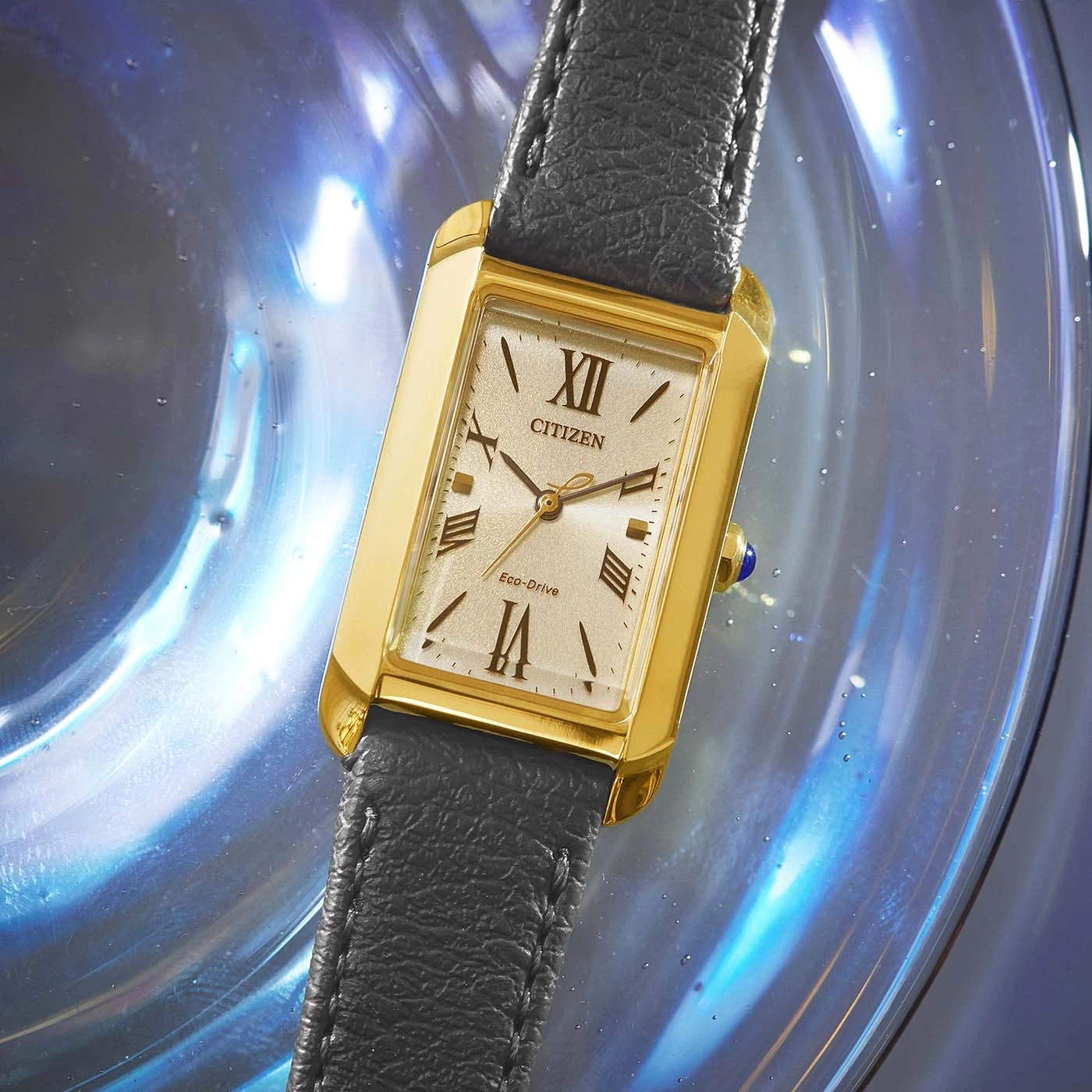 Citizen watch with gold case and black leather strap on a blue background