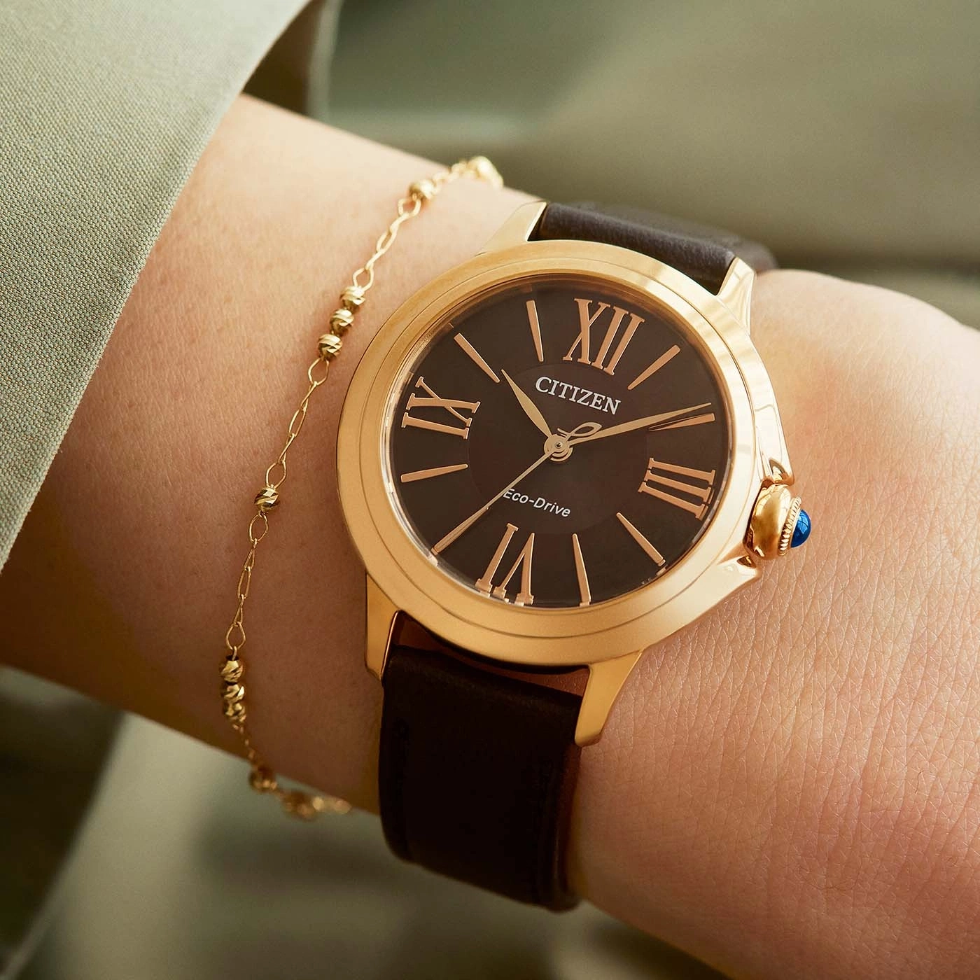 Close-up of a Citizen watch on a wrist with a gold bracelet.