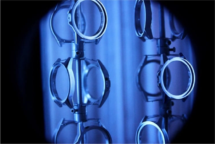Watch parts on a rack, illuminated with blue light, close-up shot.