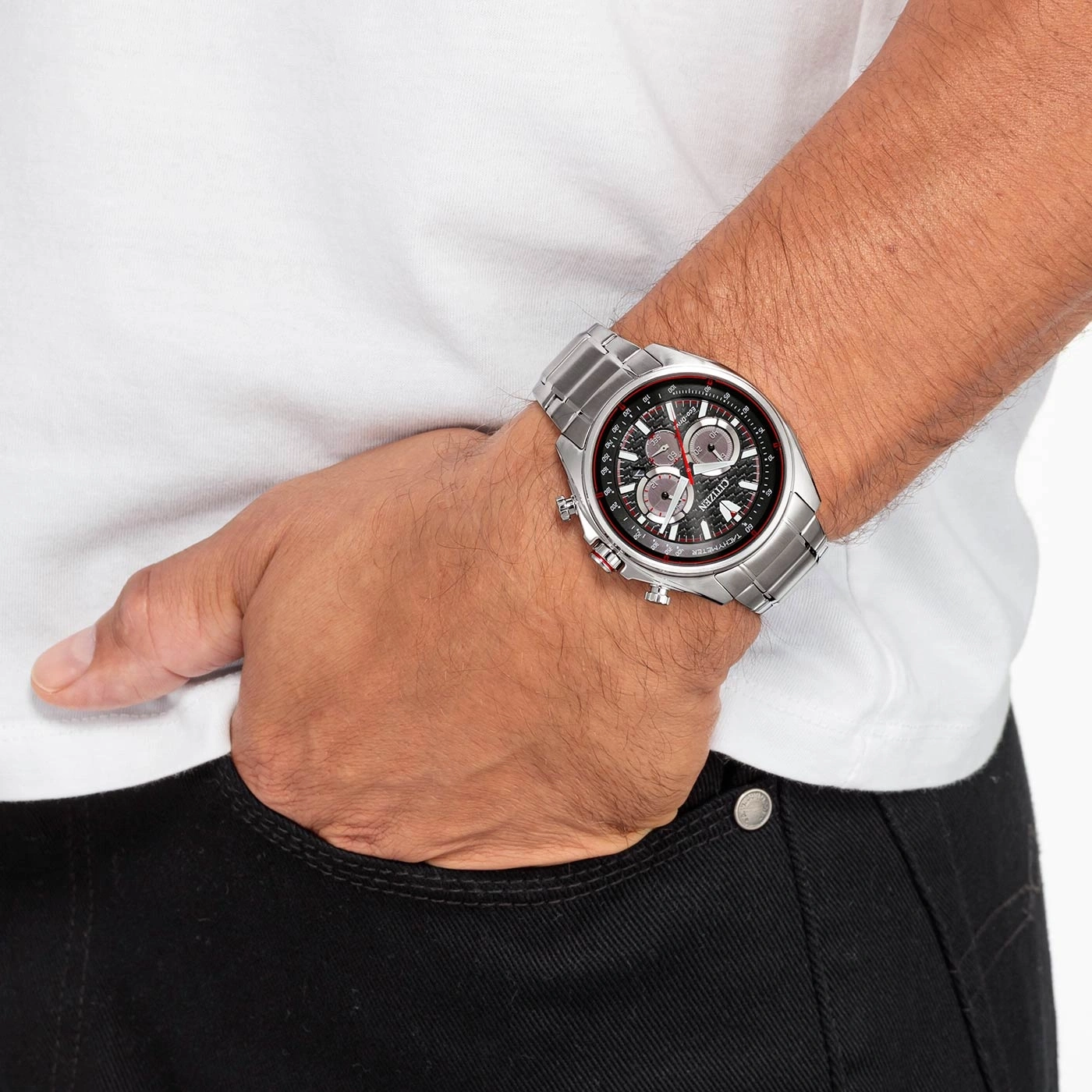 Man wearing a silver Citizen watch, white shirt, black jeans, hand in pocket.