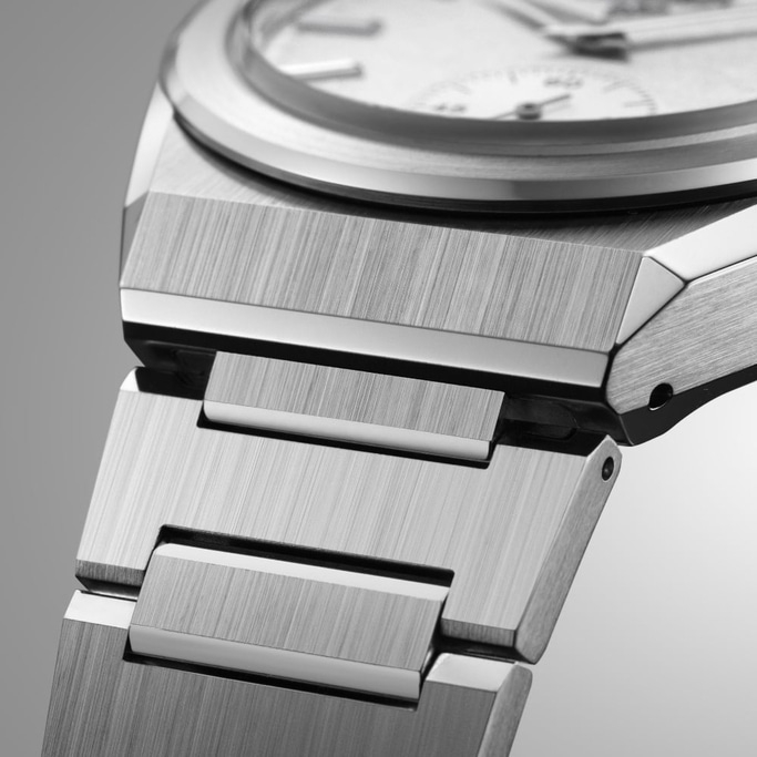 Close-up of a silver watch with a brushed metal finish and a detailed design.