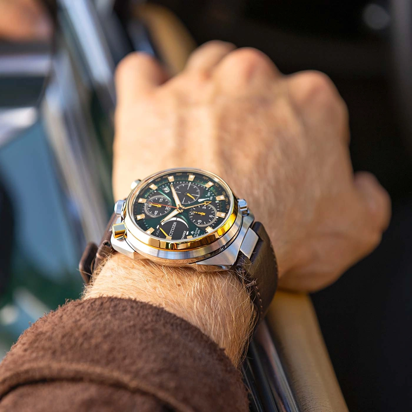 A man wearing a Citizen watch on his wrist, driving a car.