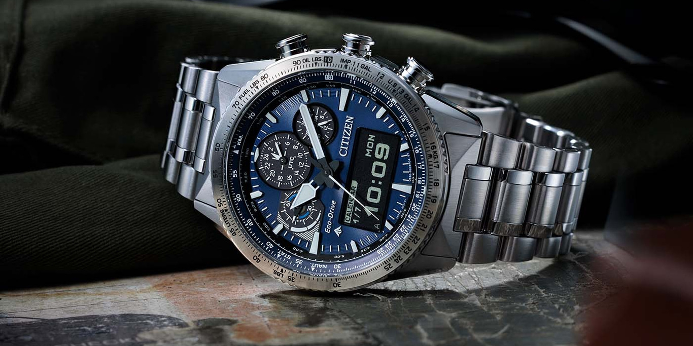 Citizen watch with blue face, digital display, and stainless steel band on a surface.