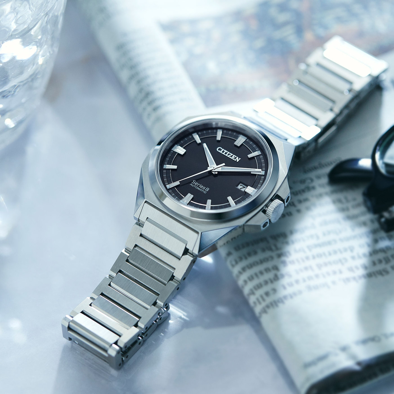Citizen Series 8 watch on newspaper, black dial, silver bracelet, elegant design