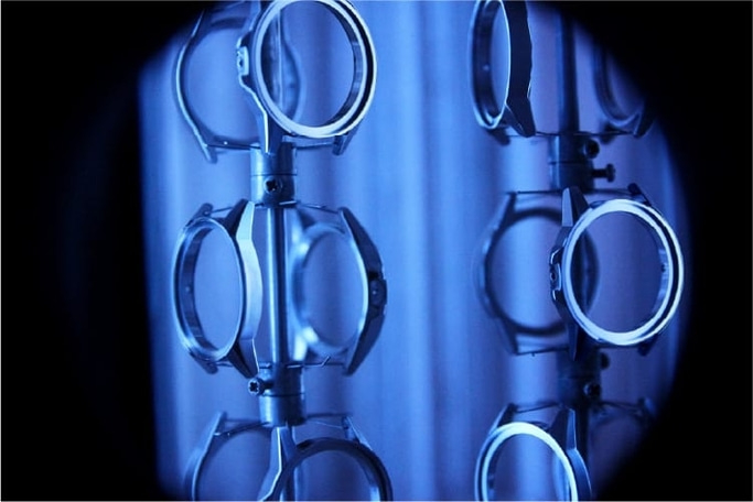 Watch parts on a rack, illuminated with blue light, close-up shot.