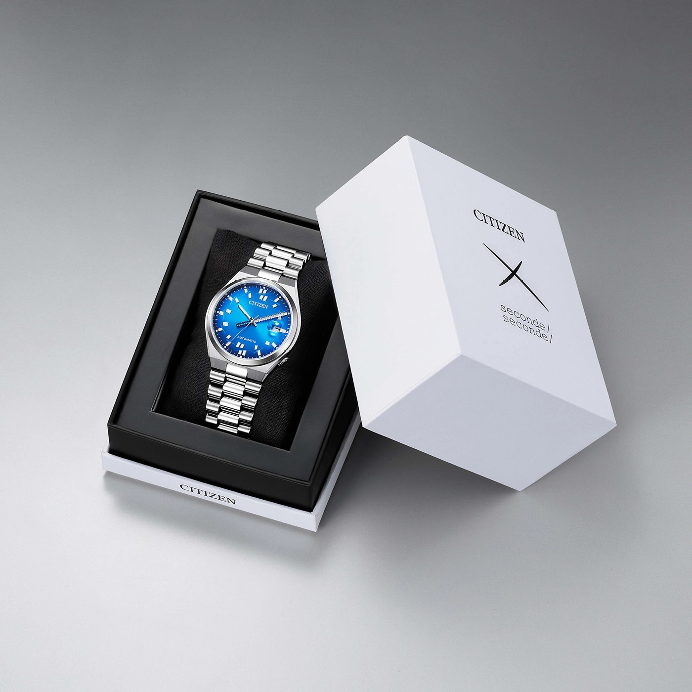 A blue Citizen watch in its box next to the packaging.