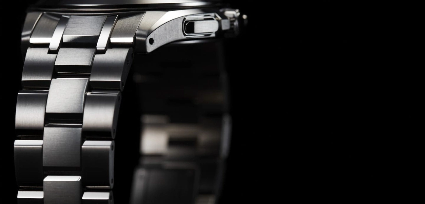Close-up of a silver watch with a black background, showing the watch's band.
