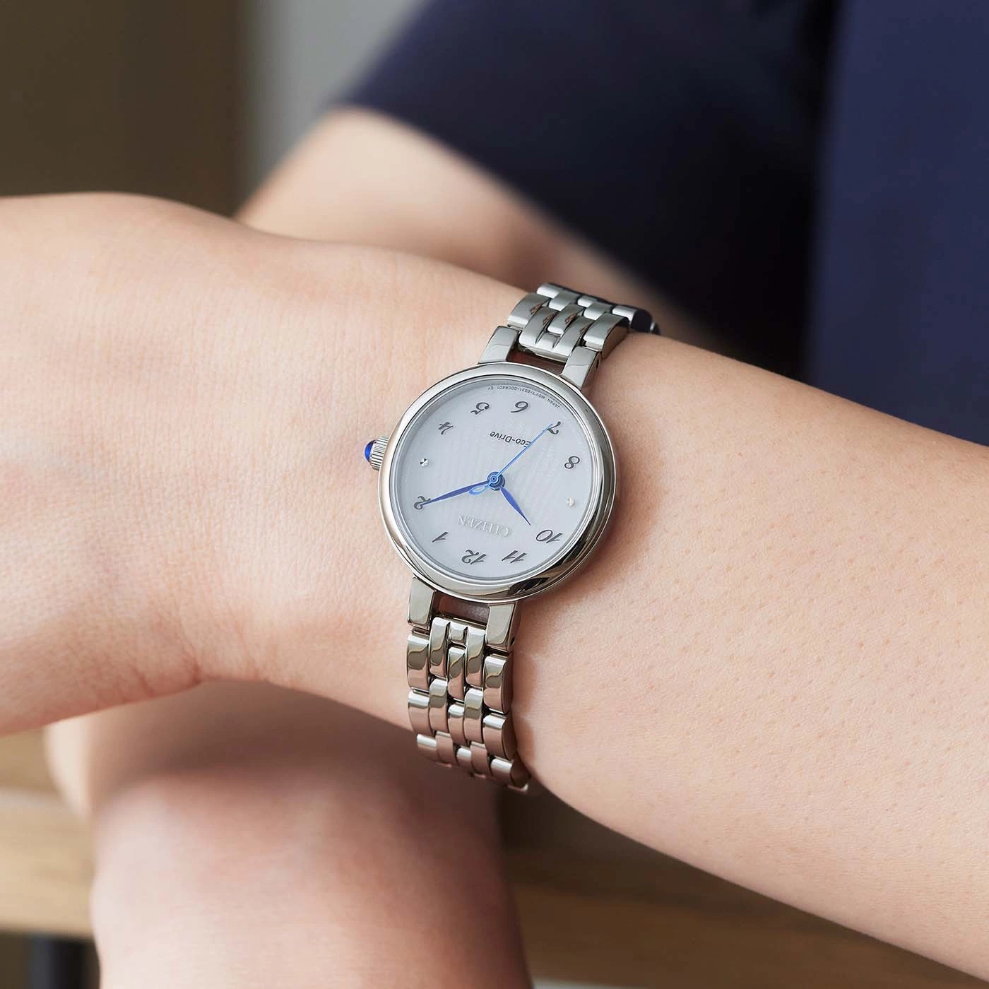 Citizen watch on wrist, silver band, white face, blue hands, elegant design