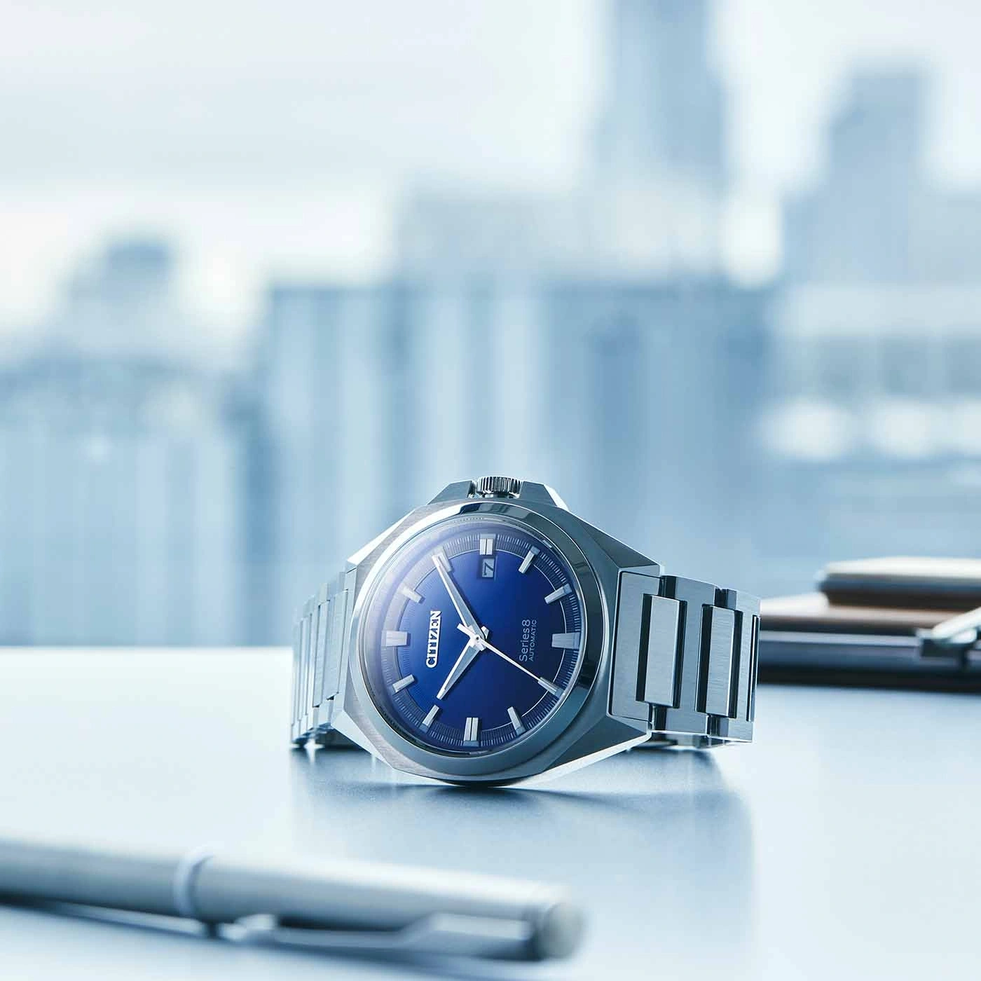 Citizen Series 8 watch with blue face on a desk with a pen.
