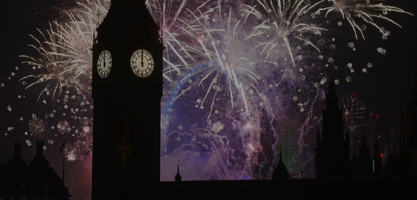 Fireworks over Big Ben and the London Eye at night, celebrating.