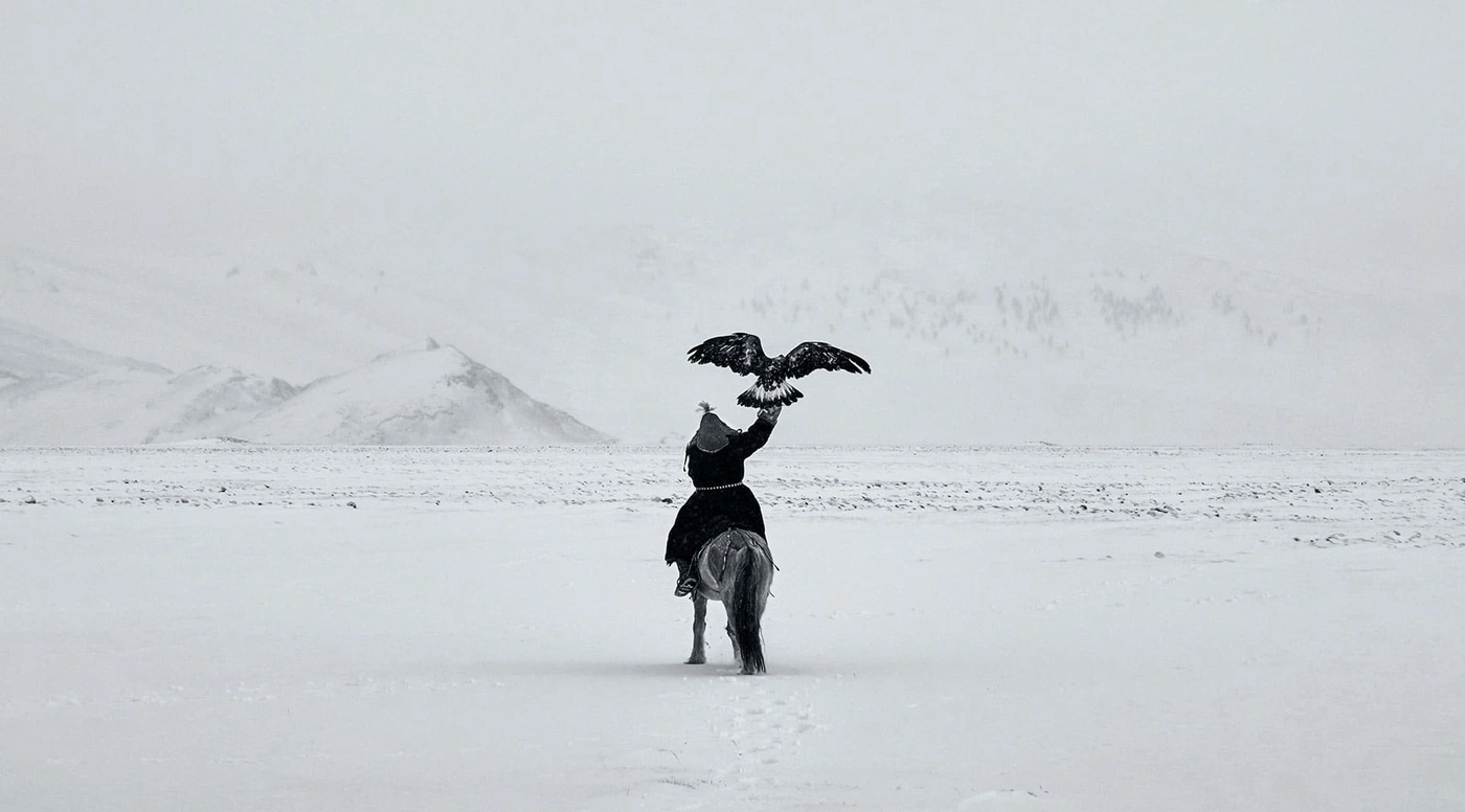 Man on horse with eagle in snowy landscape, monochrome.