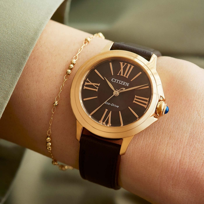 Close-up of a Citizen watch on a wrist with a gold bracelet.