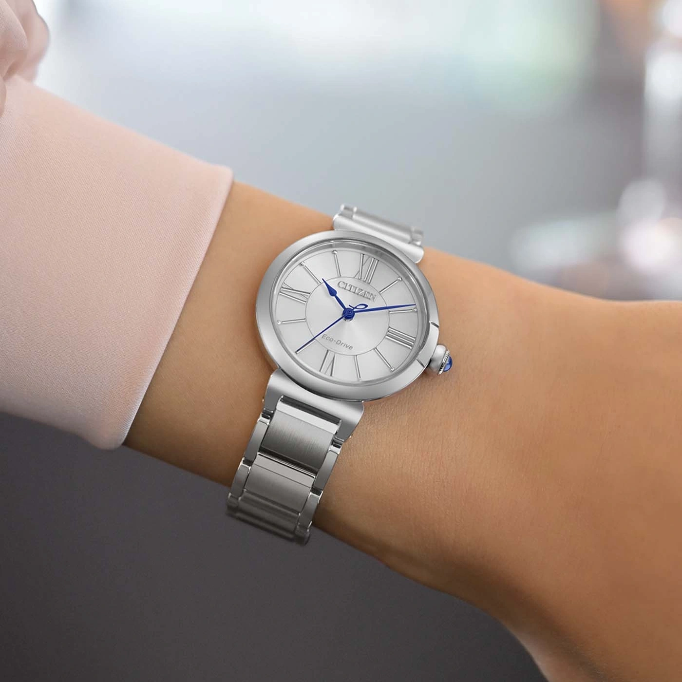 A woman wears a silver Citizen Eco-Drive watch with a Roman numeral dial.