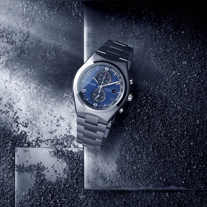 Citizen watch with blue face and titanium band on a textured surface.