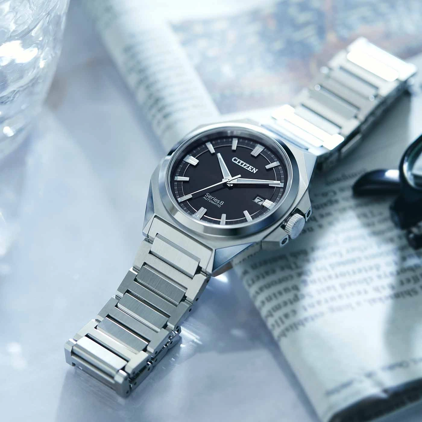 Citizen Series 8 watch on newspaper, black dial, silver bracelet, close-up shot