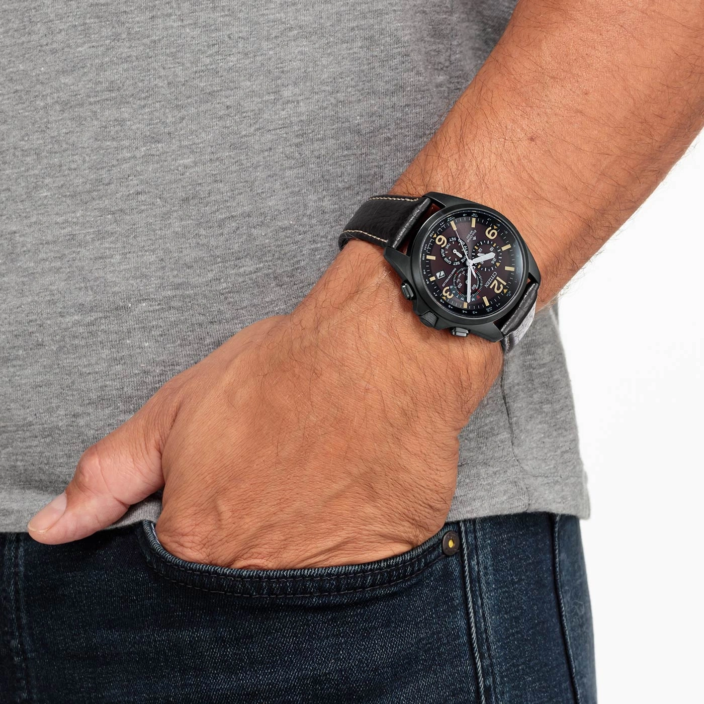 Man wearing a black watch with a leather strap, hand in pocket.