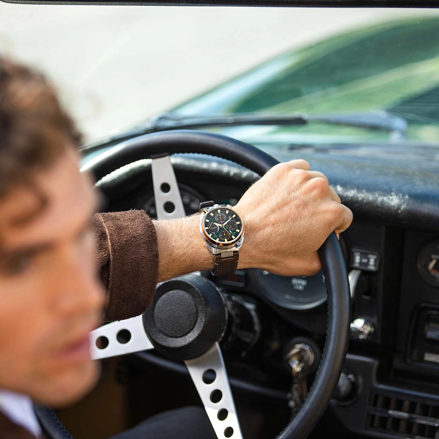 Man driving a vintage car, wearing a watch