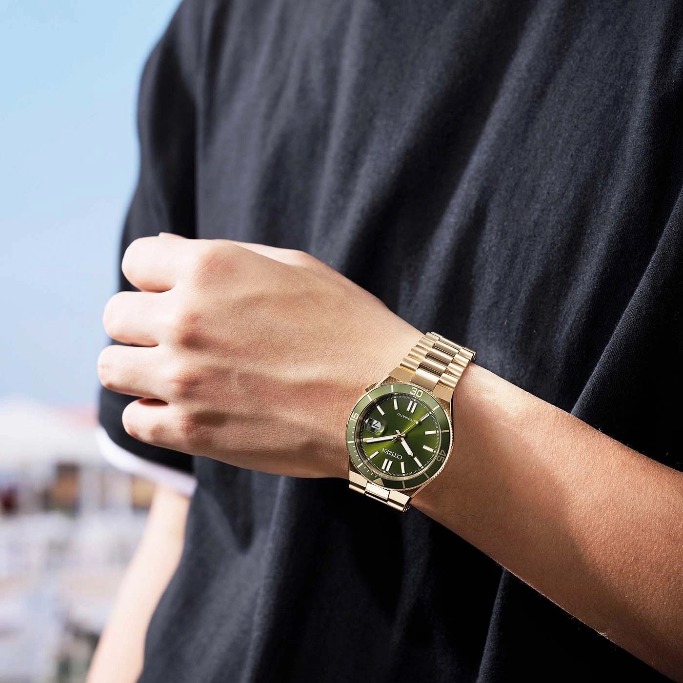 Man wearing a gold Citizen watch with a green dial.